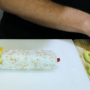 placing-mango-and-avocado-slices-on-top-of-a-sushi-roll